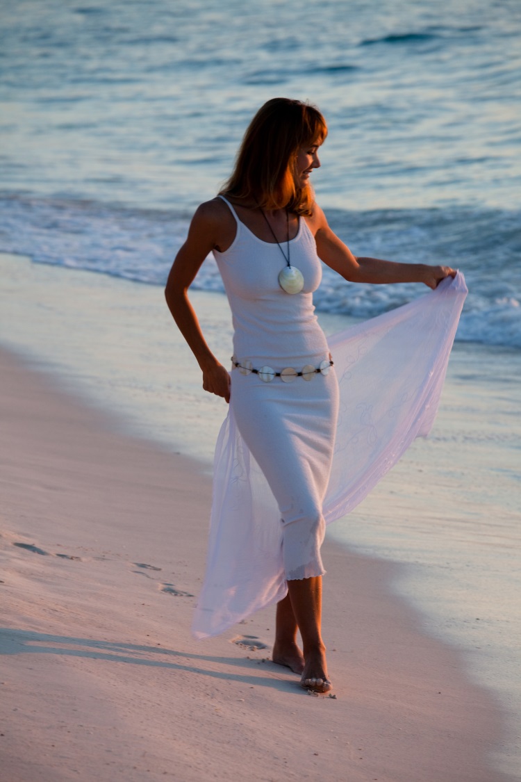 5 modele de rochii albe pentru vara 2018 - femeie in rochie alba mulata pe plaja